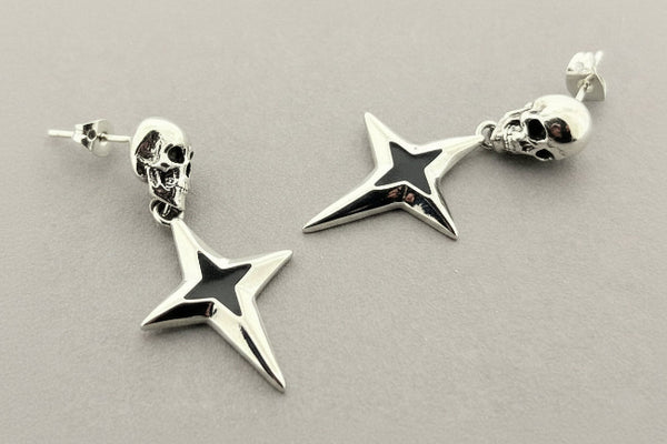 Silver star-shaped earrings with skull designs on a gray background