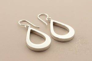Pair of silver teardrop earrings on a gray background