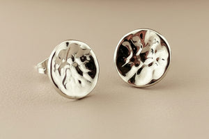 Pair of silver earrings with textured design on a gray background
