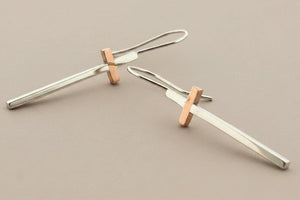 Pair of silver and rose gold earrings on a gray background