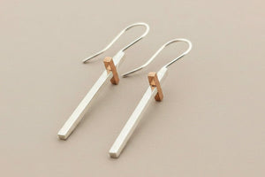 Pair of silver and rose gold earrings on a gray background