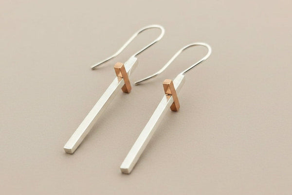 Pair of silver and rose gold earrings on a gray background