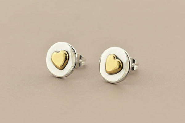 Pair of gold heart stud earrings on a gray background