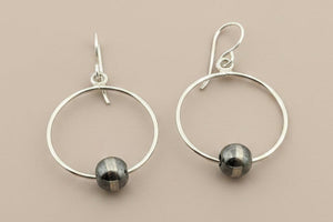 Silver hoop earrings with small round beads on a gray background