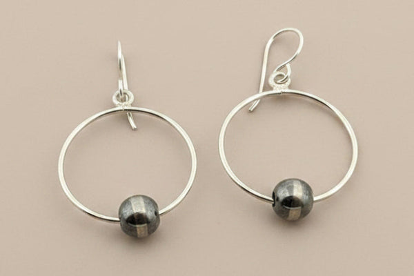 Silver hoop earrings with small round beads on a gray background