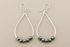 Silver hoop earrings with striped beads on a gray background