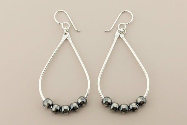 Silver hoop earrings with striped beads on a gray background