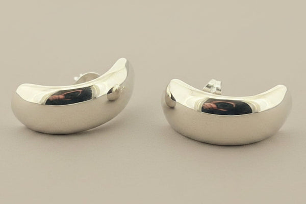 Silver hoop earrings on a gray surface