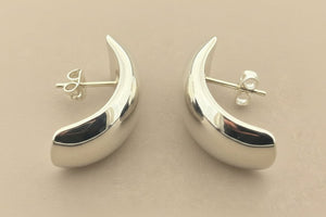 Silver crescent moon earrings on a gray background