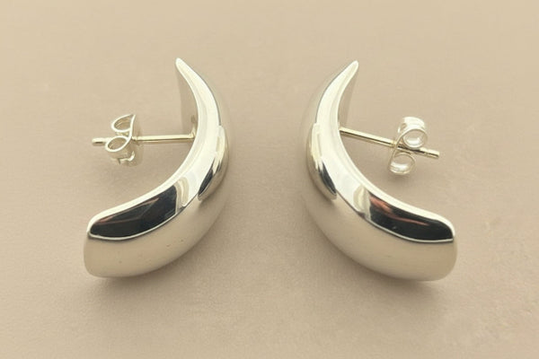 Silver crescent moon earrings on a gray background