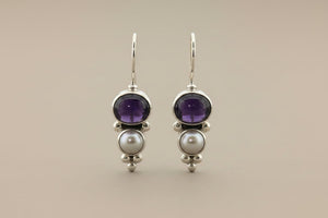 Pair of earrings with amethysts and pearls on a gray background