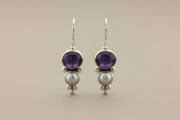 Pair of earrings with amethysts and pearls on a gray background