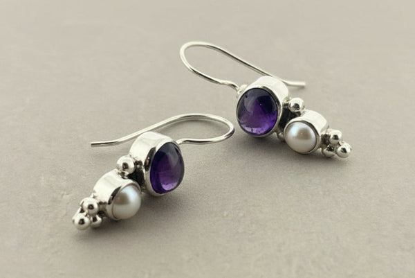 Pair of earrings with amethysts and pearls on a gray background