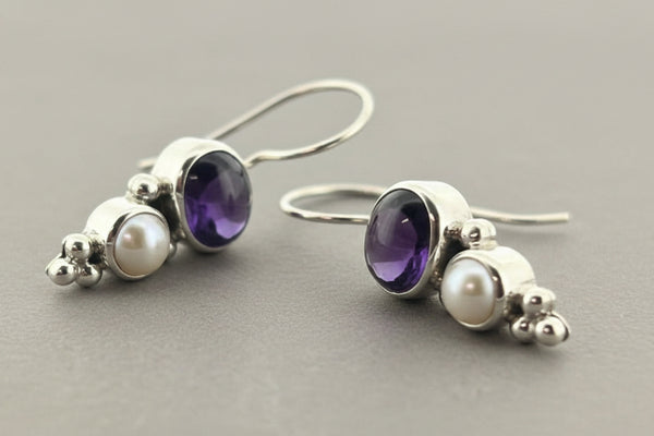 Pair of earrings with amethysts and pearls on a gray background