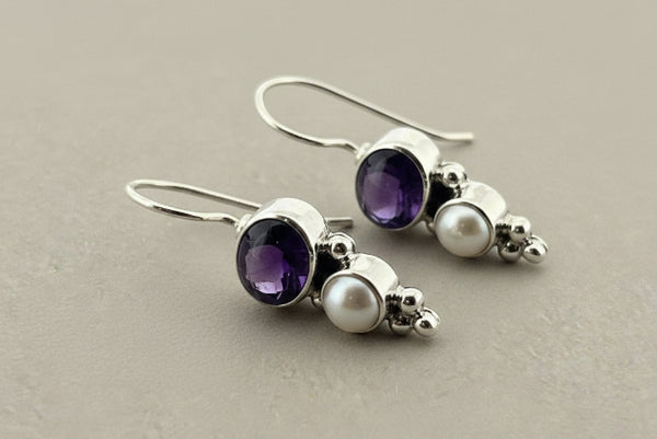 Pair of earrings with amethysts and pearls on a gray background