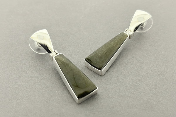 Pair of silver earrings with green stone on a gray background