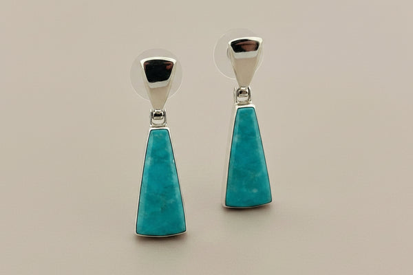 Turquoise earrings with silver hooks on a gray background