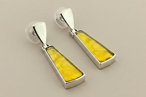 Pair of earrings with yellow and silver design on a gray background