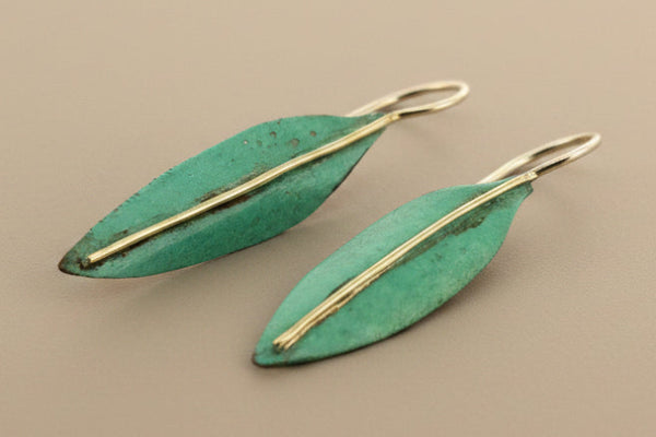 Pair of green leaf-shaped earrings on a gray background