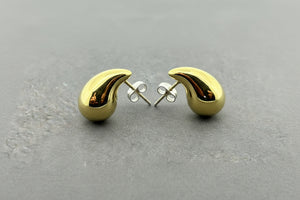 A pair of gold crescent-shaped stud earrings with silver butterfly backings, displayed on a dark gray textured surface.