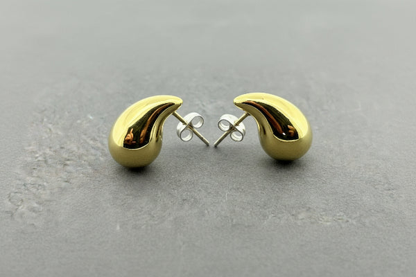 A pair of gold crescent-shaped stud earrings with silver butterfly backings, displayed on a dark gray textured surface.
