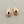 Load image into Gallery viewer, A pair of polished rose gold crescent-shaped stud earrings with butterfly backings, displayed on a textured dark gray surface.
