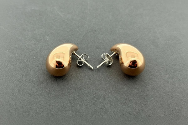 A pair of small teardrop-shaped stud earrings in a polished rose gold finish, shown with their silver butterfly backings on a dark gray textured background.