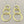 Load image into Gallery viewer, A pair of gold dangle earrings with three stacked interlocking circular rings on each earring, suspended from silver fishhook ear wires, displayed on a dark gray textured background.
