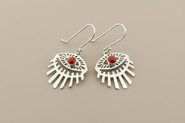 A pair of sterling silver dangle earrings with a fan-like cutout design and a small round red stone in the center, displayed on a dark gray textured background.