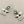 Load image into Gallery viewer, A pair of silver-toned dangle earrings featuring bird motifs with small white pearl bead clusters, displayed on a dark gray textured background.
