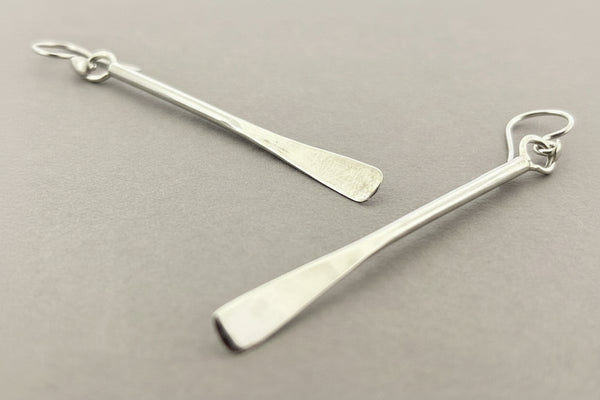 Pair of silver earrings on a gray background