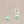 Load image into Gallery viewer, Pair of earrings with light blue pearls  and silver loops on a beige background
