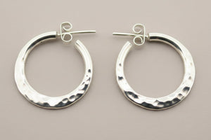 Pair of silver hoop earrings on a dark gray background