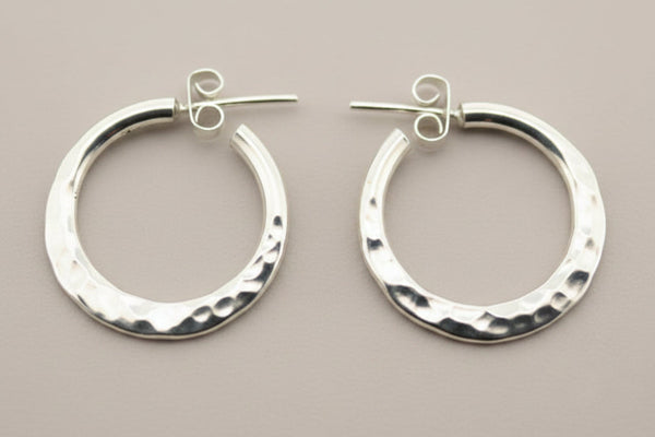 Pair of silver hoop earrings on a dark gray background