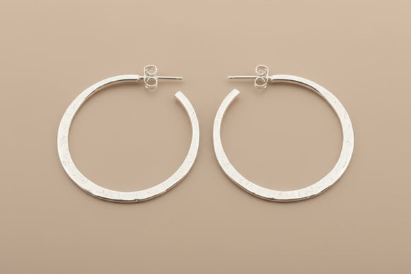 Pair of silver hoop earrings on a gray background