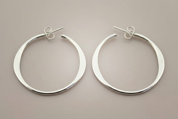 Pair of silver hoop earrings on a gray background