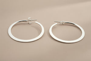 Pair of silver hoop earrings on a gray background