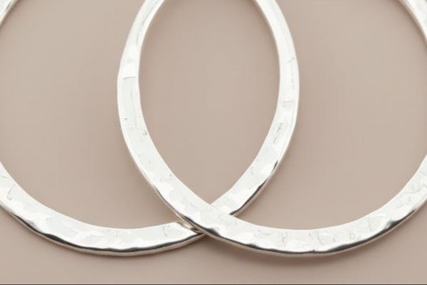 Two silver hoop earrings on a gray background