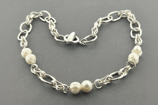 Silver chain bracelet with pearls on a gray background