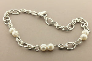 Silver chain bracelet with pearls on a gray background