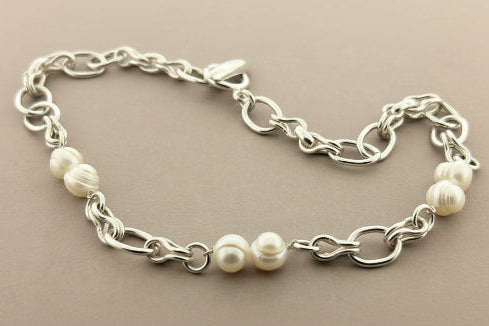 Silver chain bracelet with pearls on a gray background