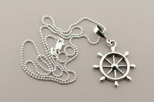 Silver necklace with a ship's wheel pendant on a gray background