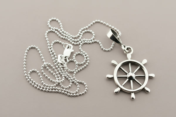 Silver necklace with a ship's wheel pendant on a gray background