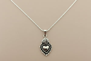 Silver necklace with a heart-shaped pendant on a gray background
