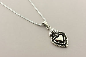 Silver necklace with a heart-shaped pendant on a gray background