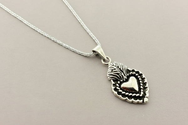 Silver necklace with a heart-shaped pendant on a gray background