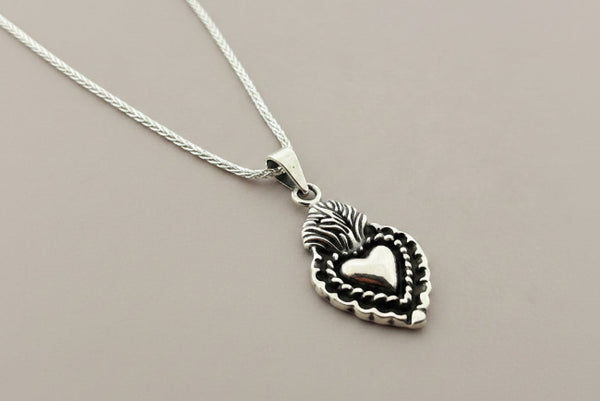 Silver necklace with a heart-shaped pendant on a gray background