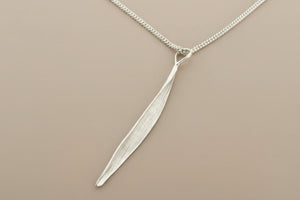 Silver leaf-shaped pendant on a chain against a gray background
