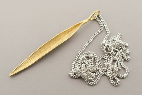 Gold pendant and silver necklace on a gray background