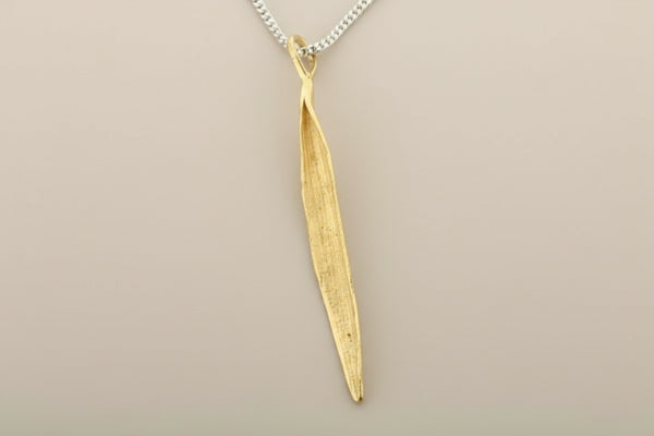 Gold leaf-shaped pendant on a chain against a gray background